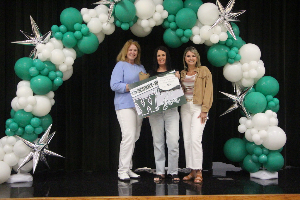 picture of three women standiing under a green and white balloon arch