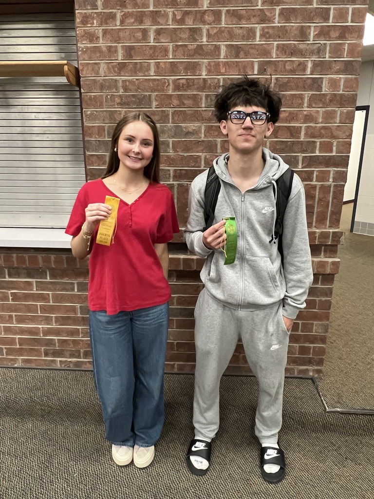 picture of female student in a red shirt holding her placement ribbon and male student in grey sweats holding his placement ribbon