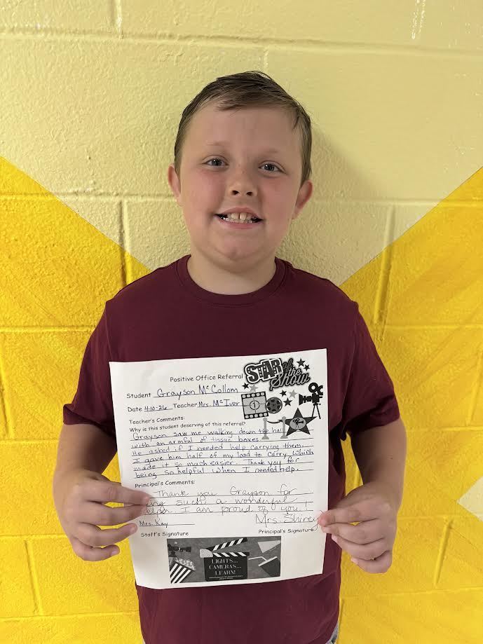 Smiliing child holding a goal celebration board.