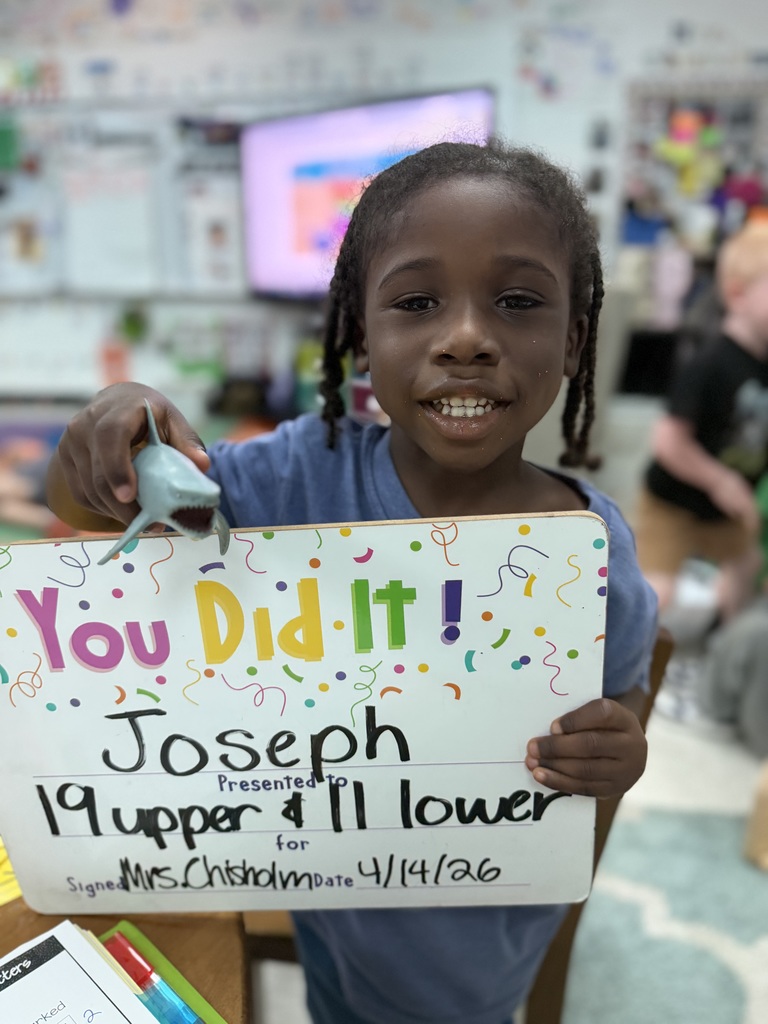 Smiliing child holding a goal celebration board.