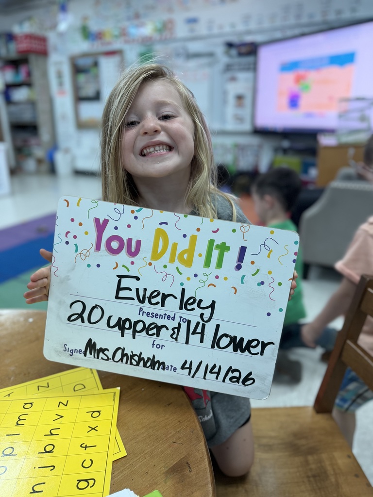 Smiliing child holding a goal celebration board.