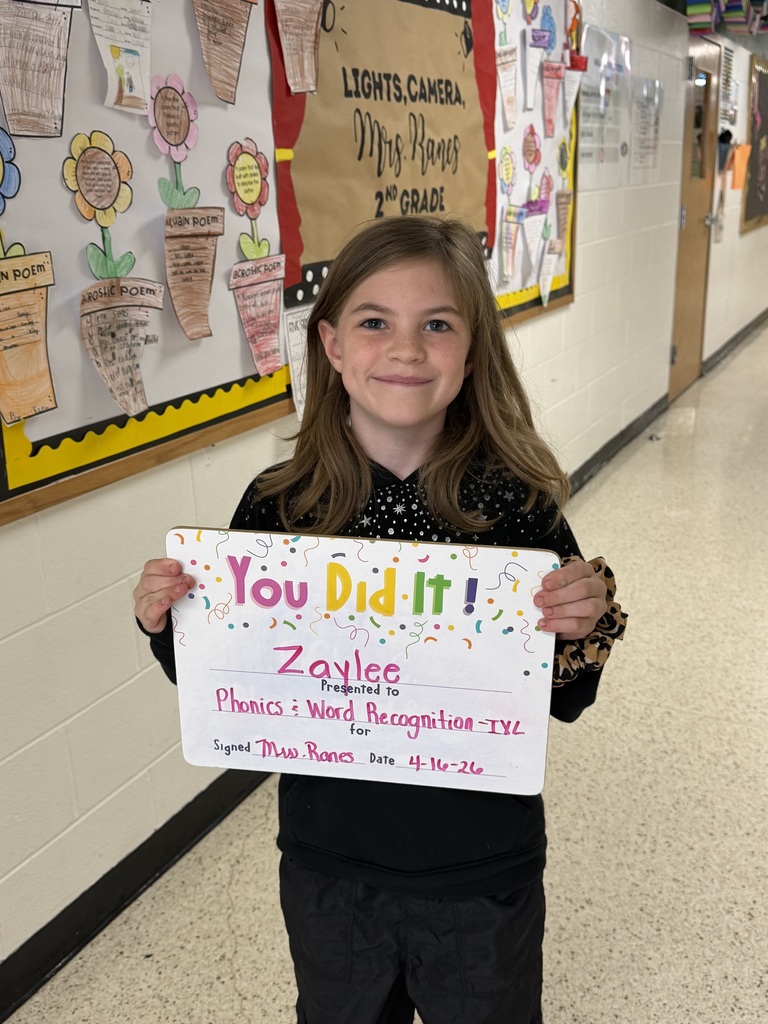 Smiliing child holding a goal celebration board.