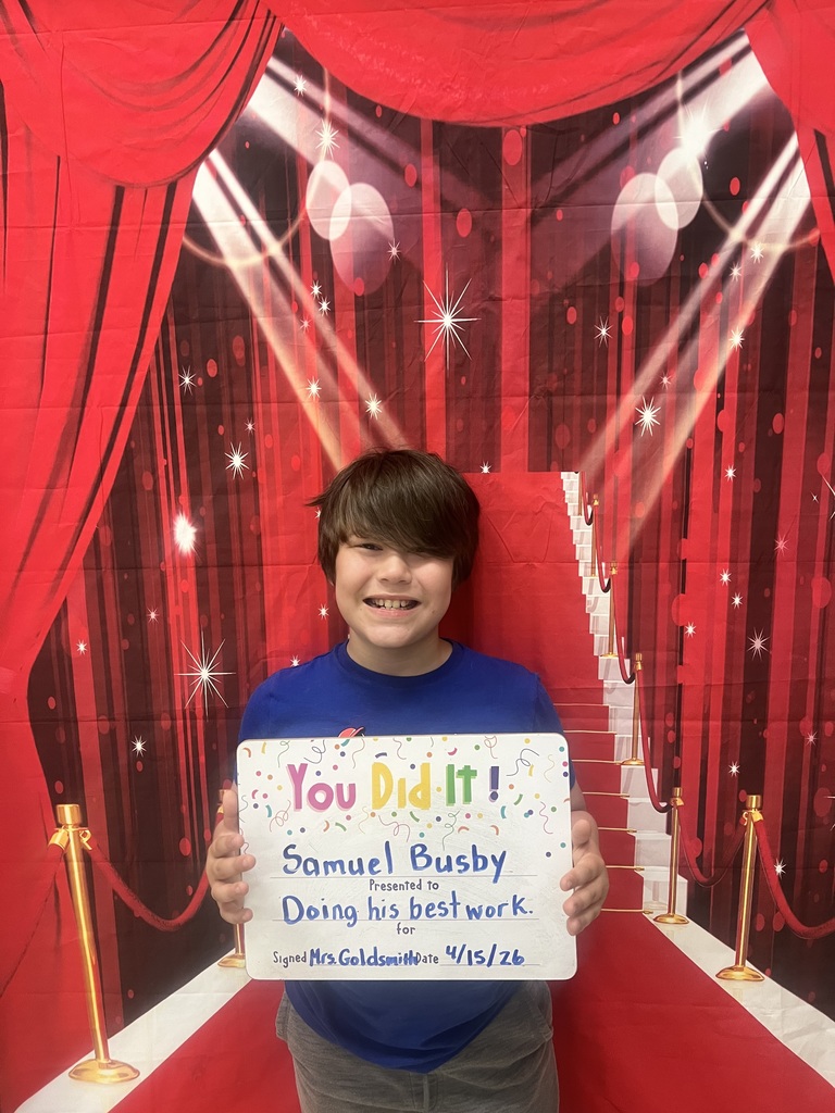 Smiliing child holding a goal celebration board.