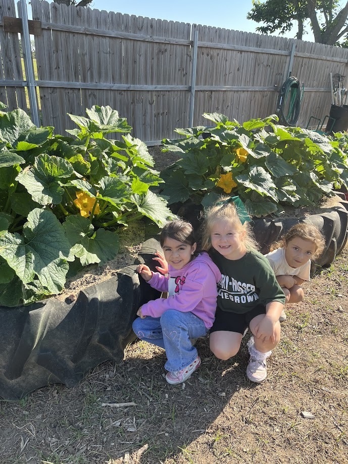 three female students posing beside zuccini plants