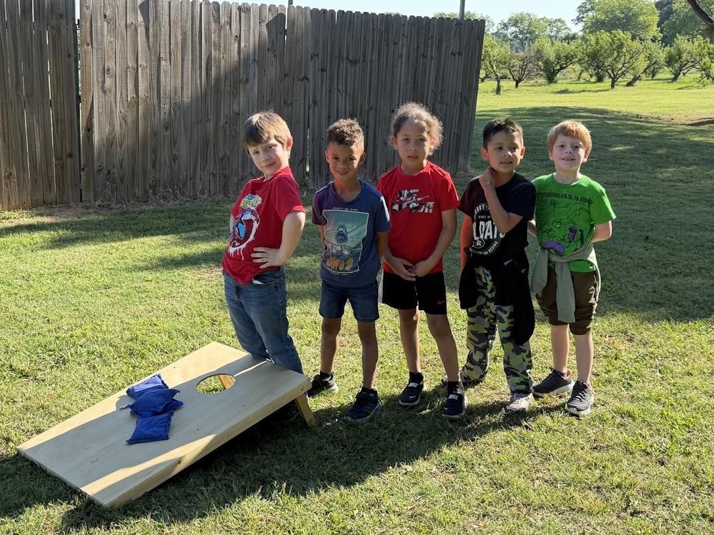 group of students posing behind a corn hole board