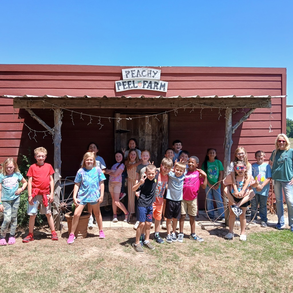 group photo of students and teacher in front of the red barn at Peachy Peel Farm