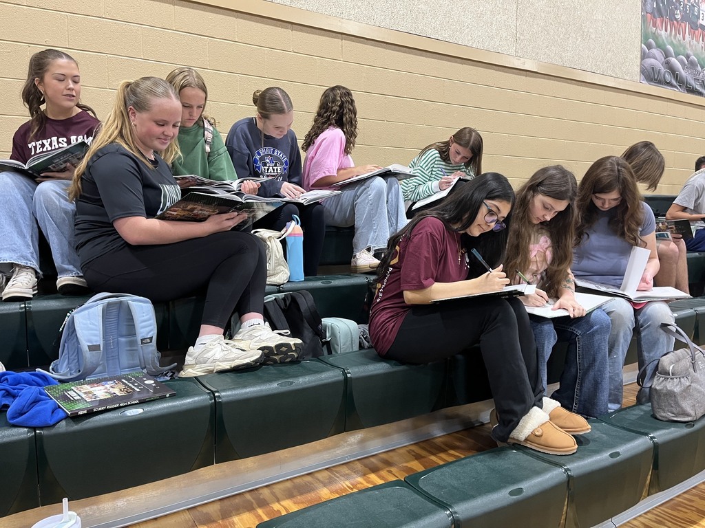 group of female students signing yearbooks in the high school gym