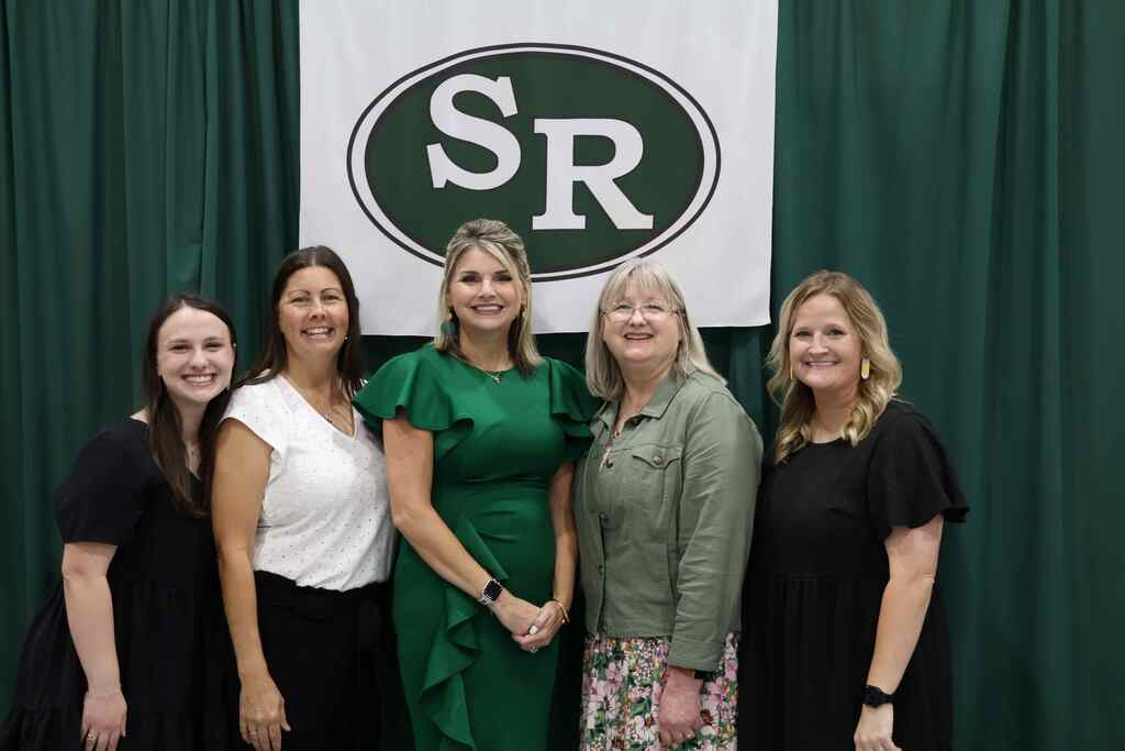 group of teacher and their principal posing for a picture before graduation 