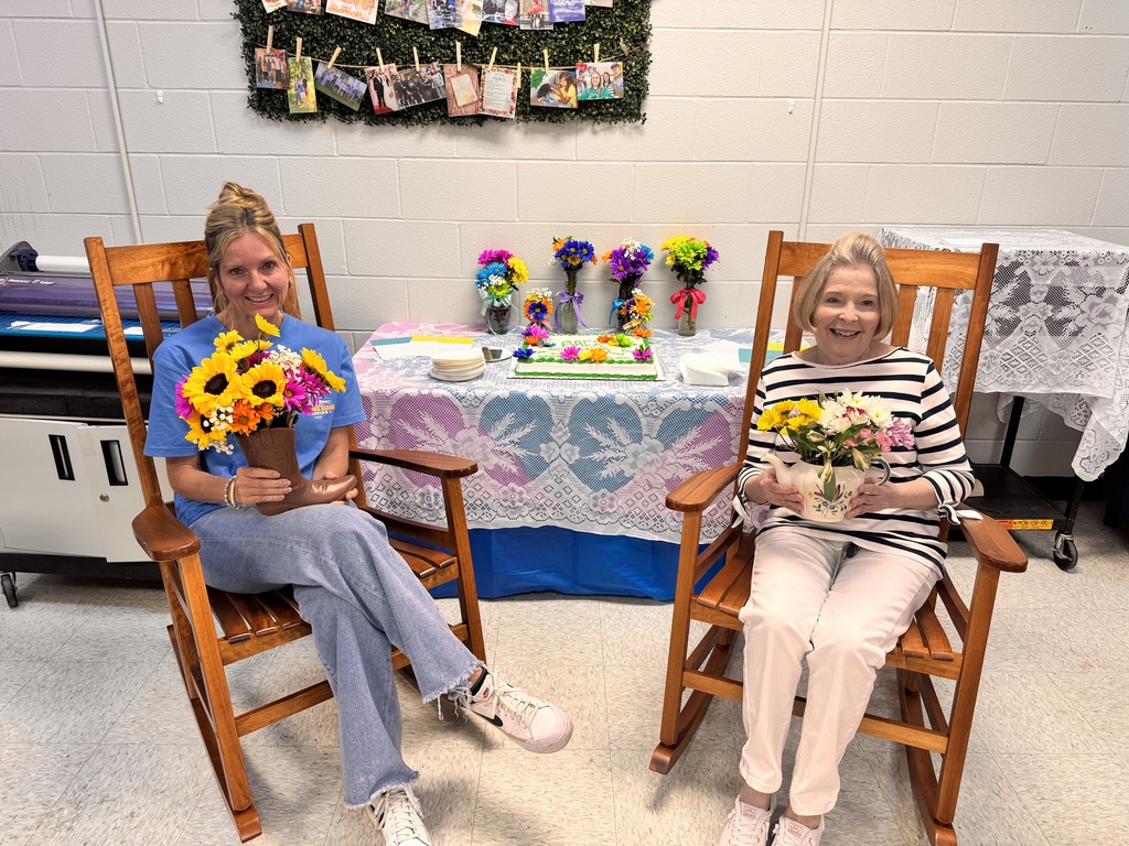 2 ladies sitting  in rockers,  holding flowers