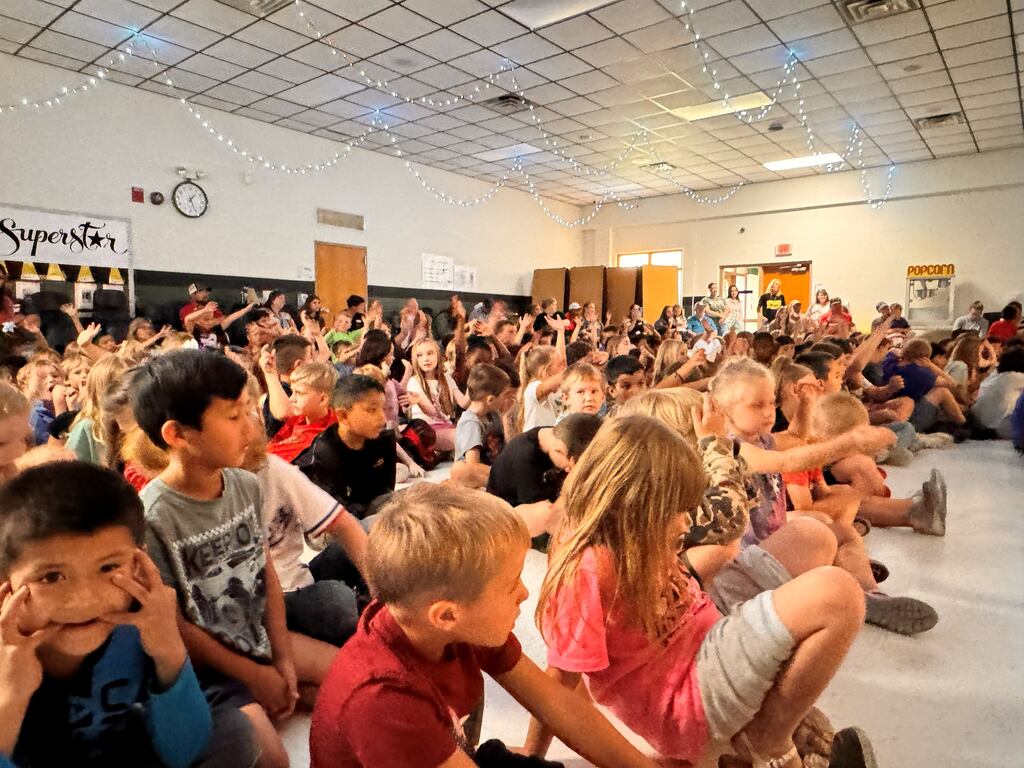 group of students sitting on the cafeteria floor watching the talent show