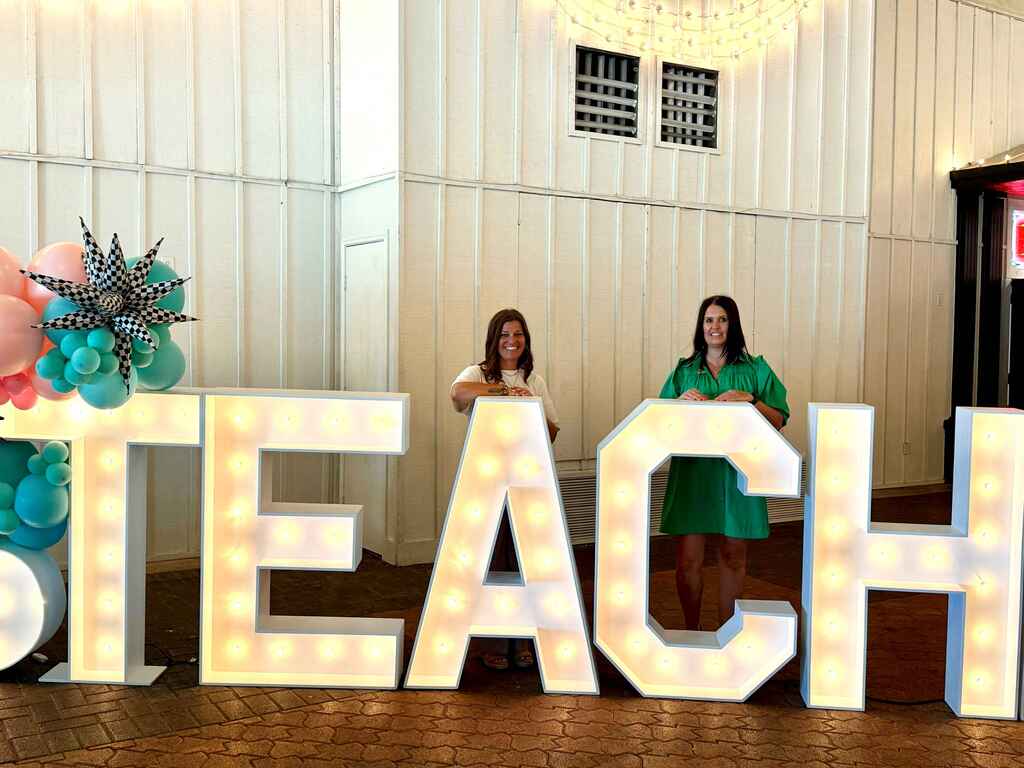 decorative image of alisha hanson and nancy muncrief standing behind lighted letters TEACH