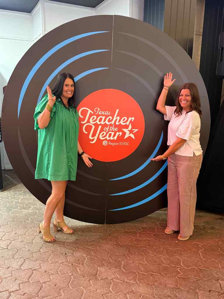 photo of nancy muncrief and alisha hanson standing in front of a record backdrop piece