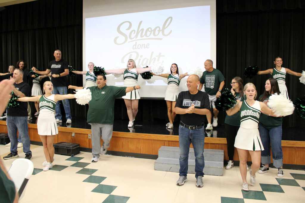 coaches and cheerleaders performing to the fight song