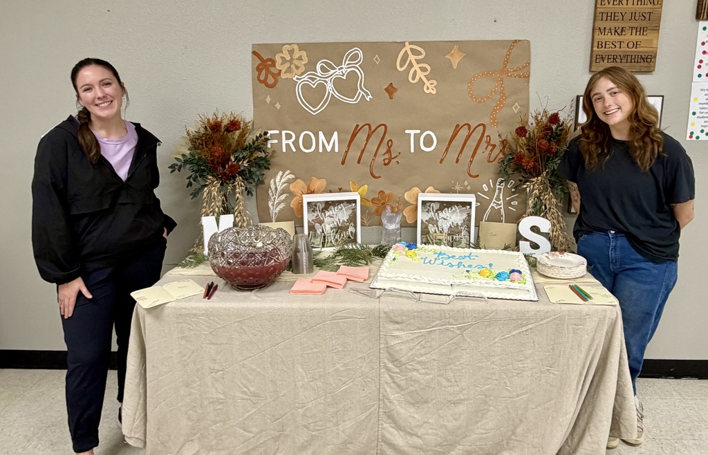 Two teachers in front of cake.