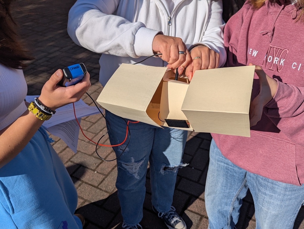 Students at Sedro-Woolley High School test solar-powered structures they built as part of a STEM Physics project. The projects are set up outdoors in the sunshine as students observe and make adjustments.