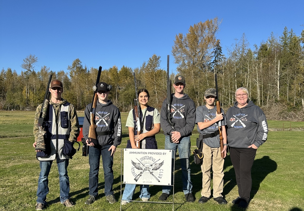 Five Sedro-Woolley High School FFA Trap Team members—Tyce Croucher, Caleb Bethea, Kaden Butcher, Douglas Fraser, and Maddy Weyand—stand together at the Old Skagit Gun Club after the District Championship, smiling and wearing their team gear.