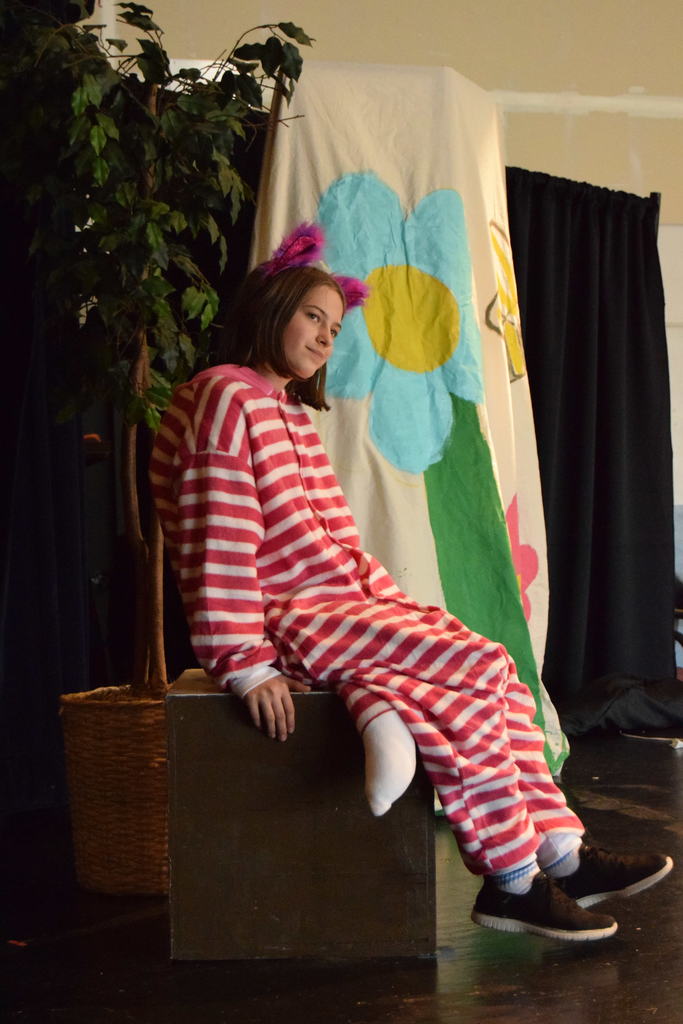 Cascade Middle School drama students in costume rehearsing for “Dorothy in Wonderland,” with characters from The Wizard of Oz and Alice in Wonderland gathered on stage under colorful lights.