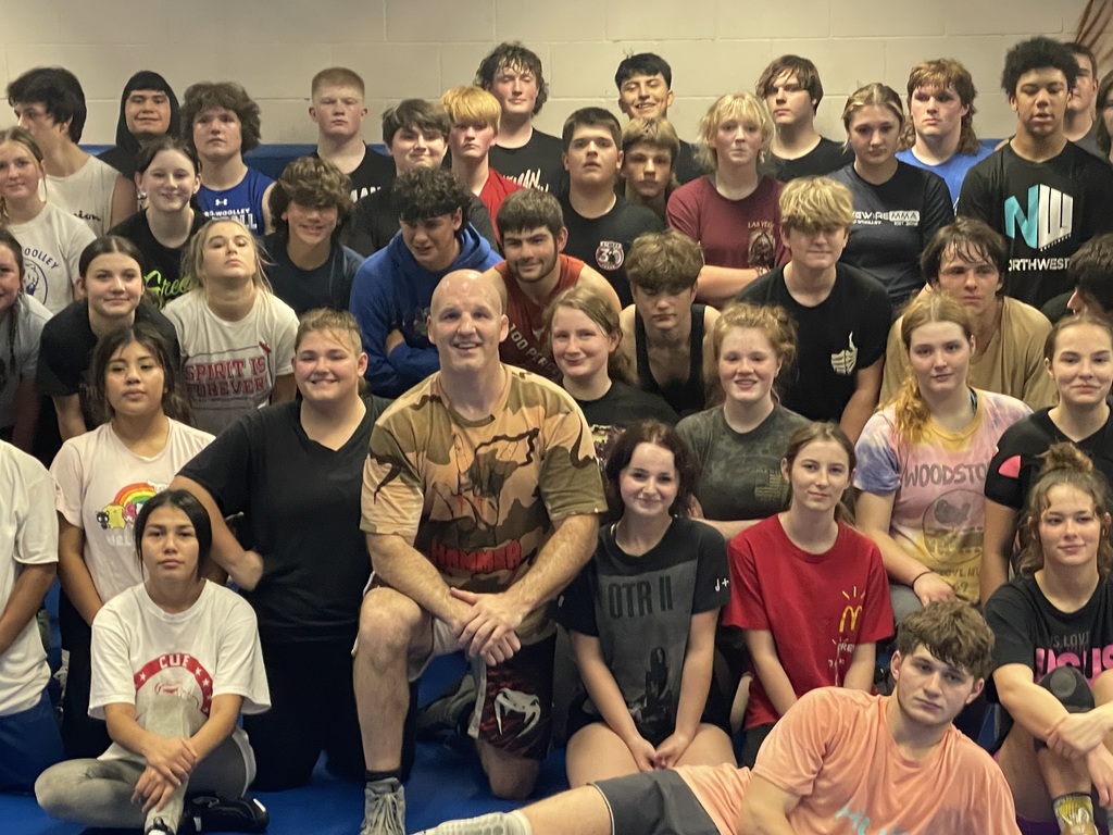 Matt Hamill smiles alongside Sedro-Woolley High School students during a previous visit to the school, standing in the gym surrounded by excited students and staff.