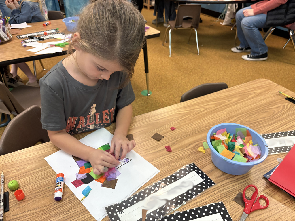 A student works on a stain glass being fashioned out of tissue paper. 