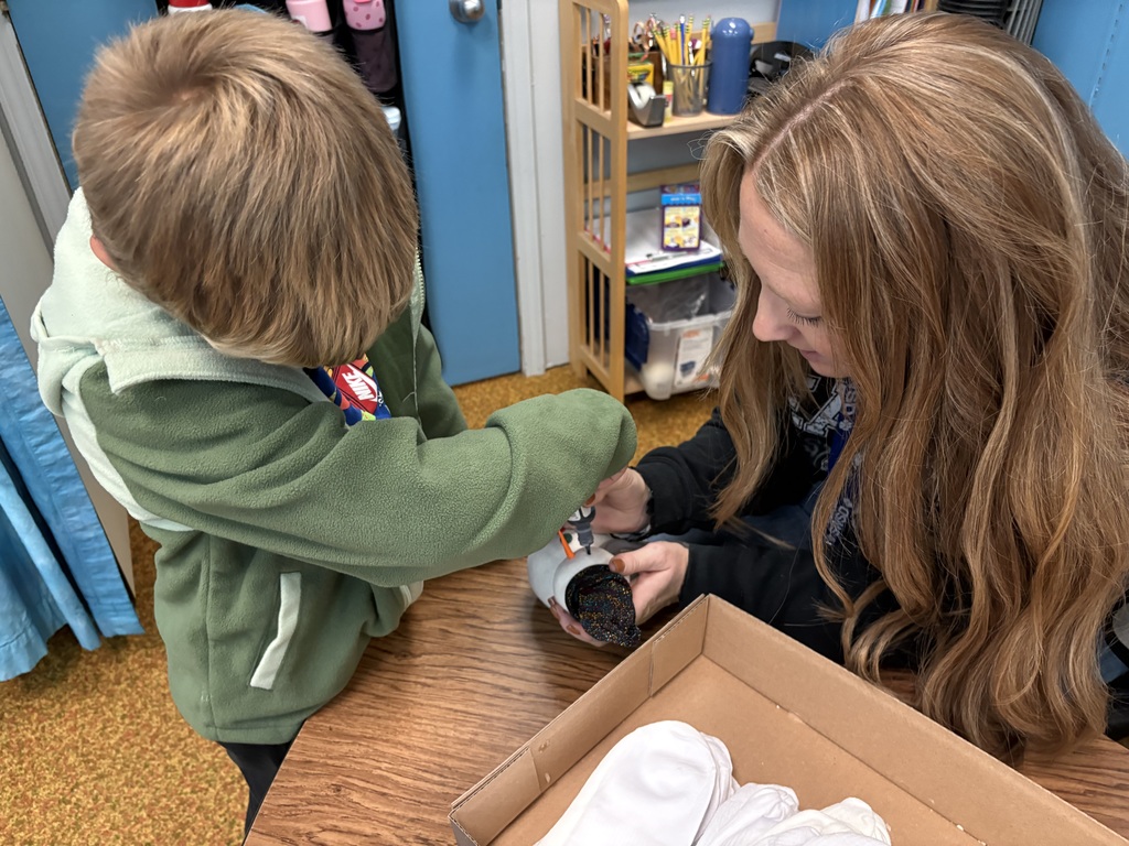 Adding some puffy paint eyes and mouth to a snowman. 