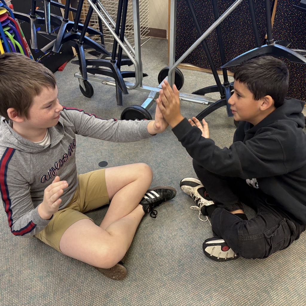 Sixth grade students at Central Elementary practice rhythmic clapping and partner high-fives during music class with their teacher.