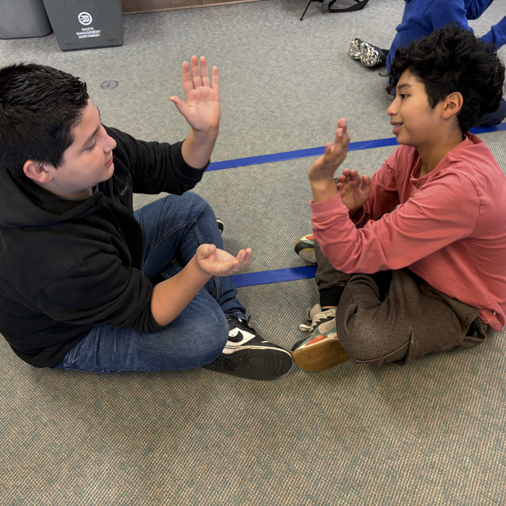 Sixth grade students at Central Elementary practice rhythmic clapping and partner high-fives during music class with their teacher.