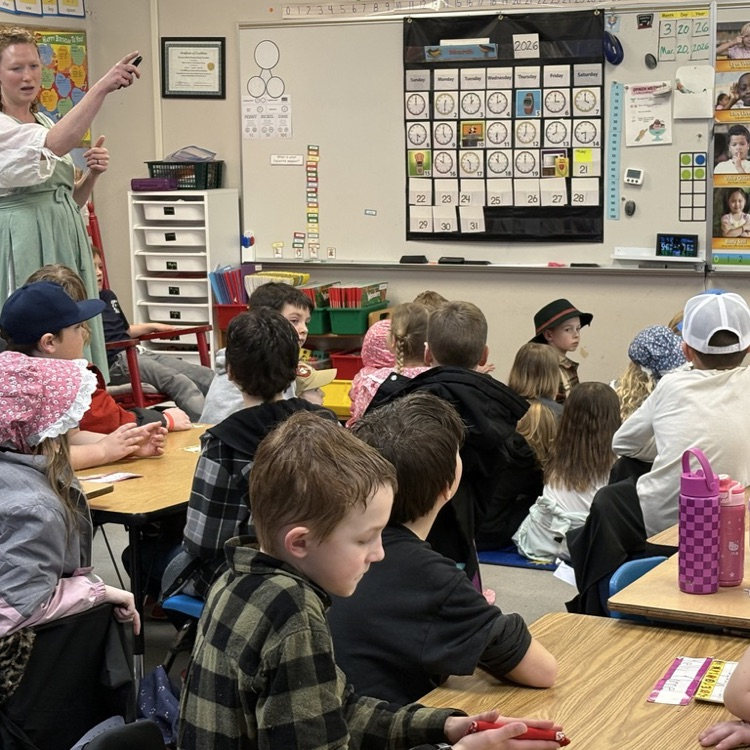 Parent volunteer Lindy Mullen Doyle taught students about the town's history. Students gathered around a slideshow showing historic photos and maps of Lyman, Washington.