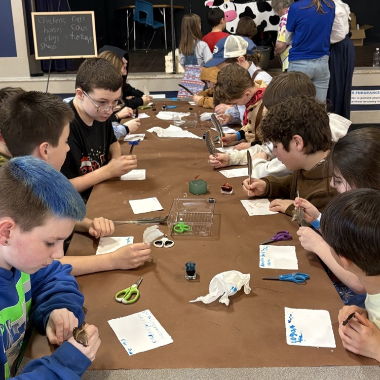 Lyman student swriting with a feather quill dipped in ink.
