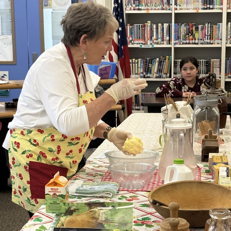 A volunteer teaching students about how to make butter