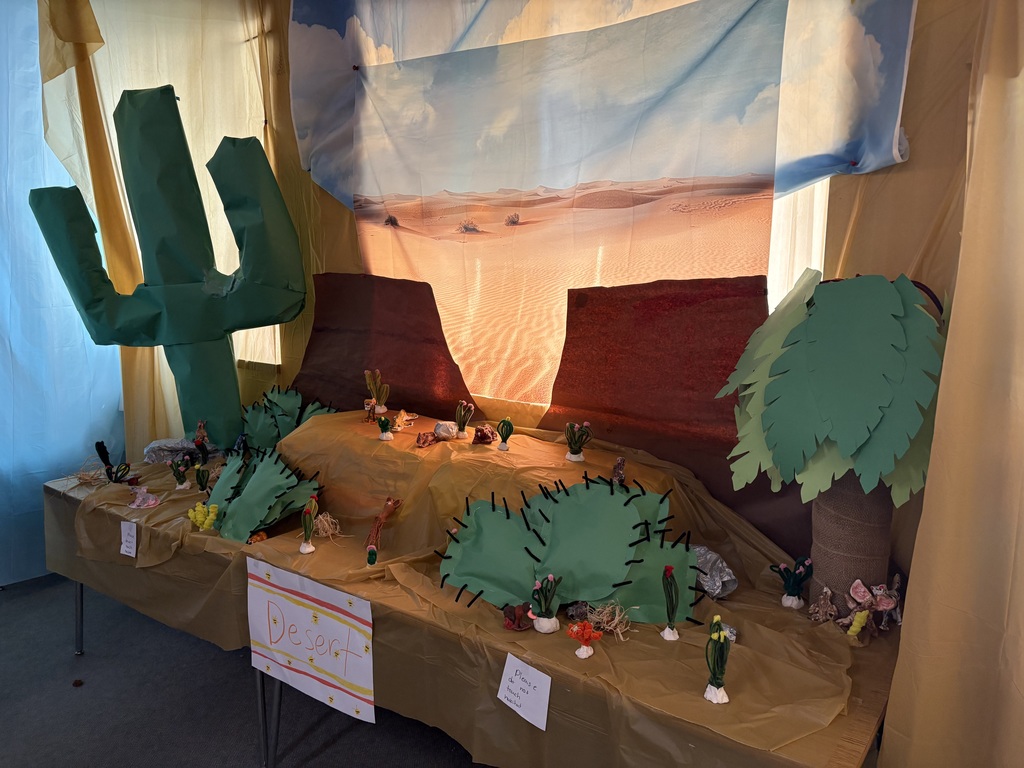 A large desert diorama with sand-colored features, plants, and animal models, illustrating how animals adapt to hot, dry environments.