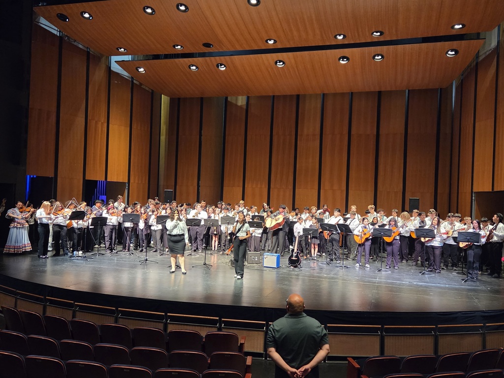 Students from several local schools perform mariachi music and folklórico dance on stage at McIntyre Hall during a regional Mariachi Festival. Photos show student musicians in traditional mariachi attire performing with instruments and large combined group performances celebrating music and culture.