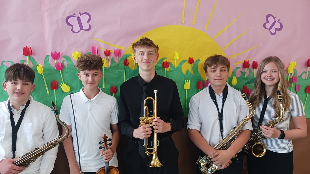 A group of middle school student musicians pose together at an honor band and orchestra event after participating in a regional performance.