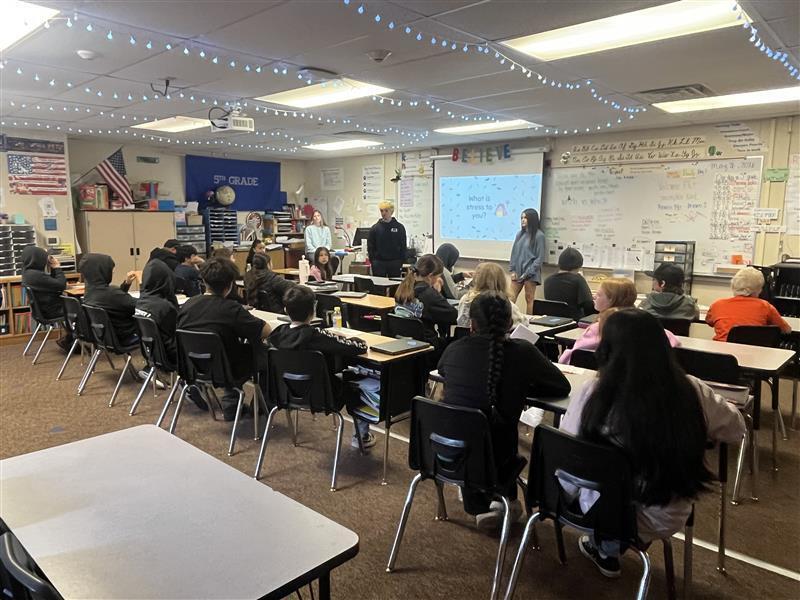Five Cascade Middle School Peer 2 Peer student leaders stand at the front of a classroom at Mary Purcell Elementary School while presenting a lesson on healthy ways to cope with stress. Elementary students listen and participate as the middle school students share prevention and wellness strategies as part of the Peer 2 Peer program.