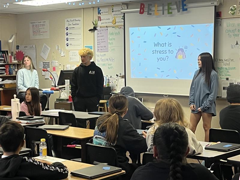 Five Cascade Middle School Peer 2 Peer student leaders stand at the front of a classroom at Mary Purcell Elementary School while presenting a lesson on healthy ways to cope with stress. Elementary students listen and participate as the middle school students share prevention and wellness strategies as part of the Peer 2 Peer program.
