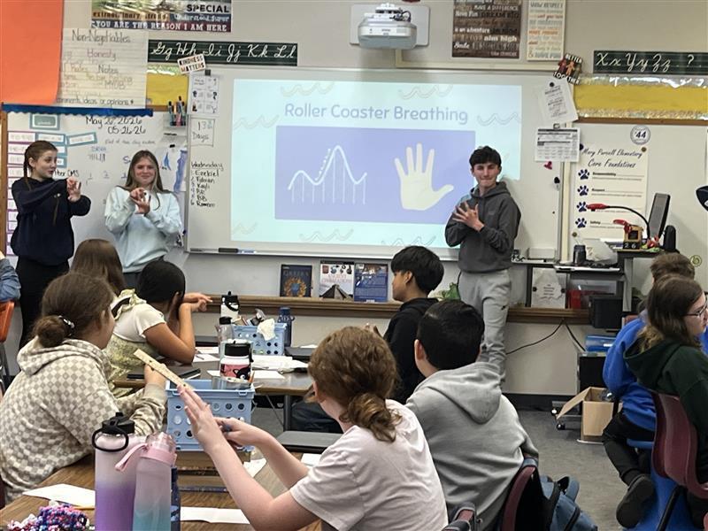 Five Cascade Middle School Peer 2 Peer student leaders stand at the front of a classroom at Mary Purcell Elementary School while presenting a lesson on healthy ways to cope with stress. Elementary students listen and participate as the middle school students share prevention and wellness strategies as part of the Peer 2 Peer program.