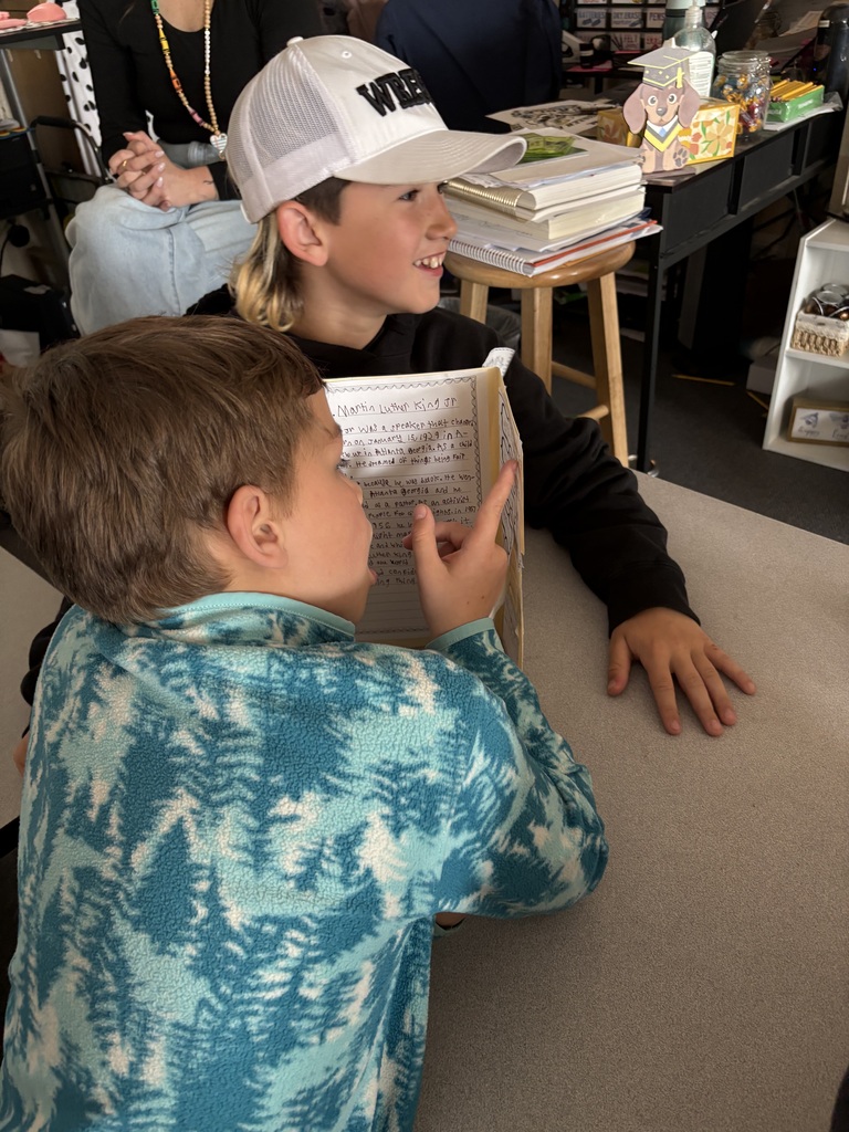 Third grade students at Evergreen STEM Elementary stand beside biography displays and presentation boards, sharing research projects about notable historical and contemporary figures with visitors during the school’s first Biography-palooza event.