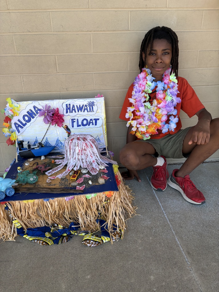 Evergreen STEM Elementary fourth grade students stand beside colorful state-themed floats they created for the annual Float Parade. The projects feature maps, landmarks, state symbols, and other research-based displays as students share information about their assigned states with visitors.