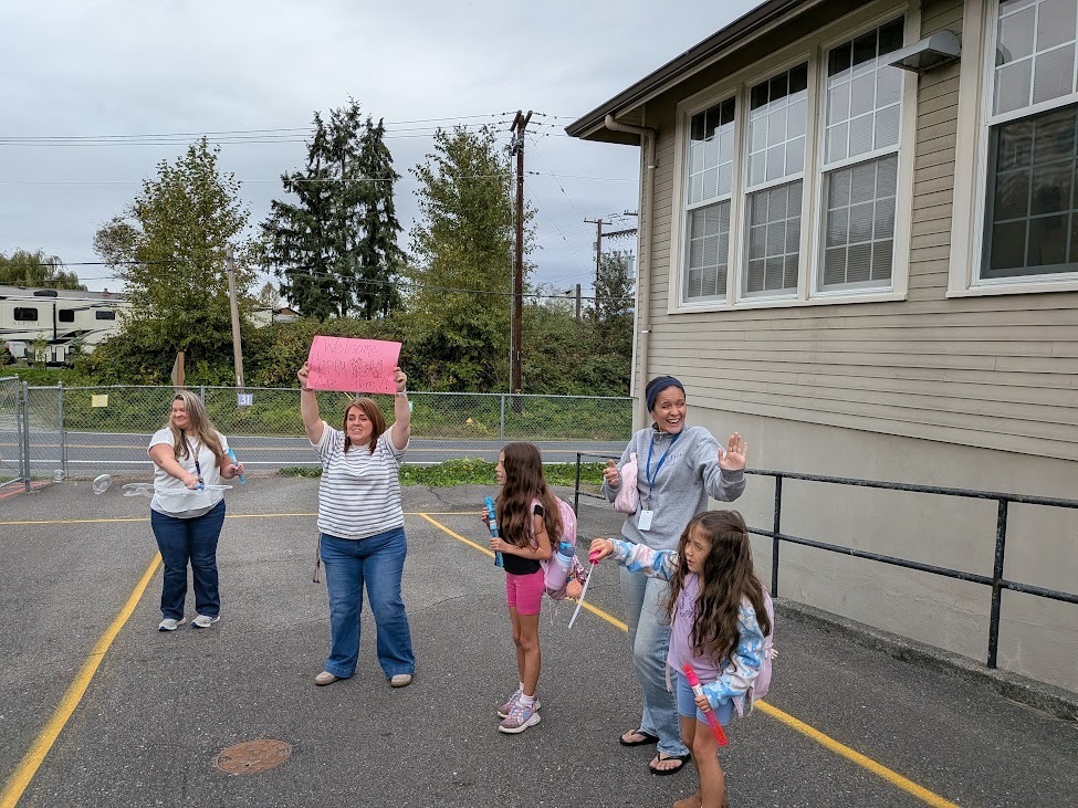 Big Lake Elementary staff welcome students during Surprise Attendance Day with music, bubbles, signs and cheers as students arrive at school.