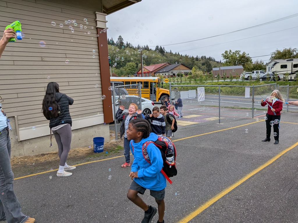 Big Lake Elementary staff welcome students during Surprise Attendance Day with music, bubbles, signs and cheers as students arrive at school.