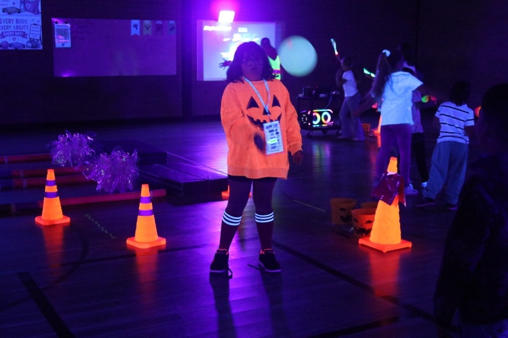 Scare Square: Students play a glow-in-the-dark version of four-square, hitting a ball between squares marked on the gym floor under black lights.