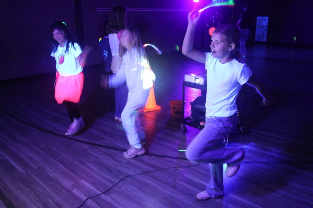 Ghostbusters Dance: Students follow dance moves displayed on a screen in the darkened gymnasium during the Ghostbusters Dance station at Evergreen STEM Elementary.