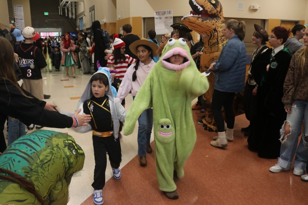 Evergreen Elementary School students dressed in Halloween costumes parade through the hallways of Cascade Middle School. Middle school students, many also in costume, line the hallways to exchange high fives and fist bumps with younger students. Other photos capture happy reunions between former Evergreen students and staff members.