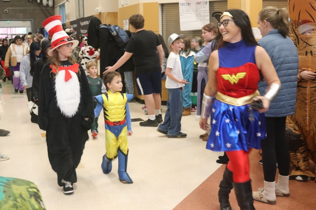 Evergreen Elementary School students dressed in Halloween costumes parade through the hallways of Cascade Middle School. Middle school students, many also in costume, line the hallways to exchange high fives and fist bumps with younger students. Other photos capture happy reunions between former Evergreen students and staff members.