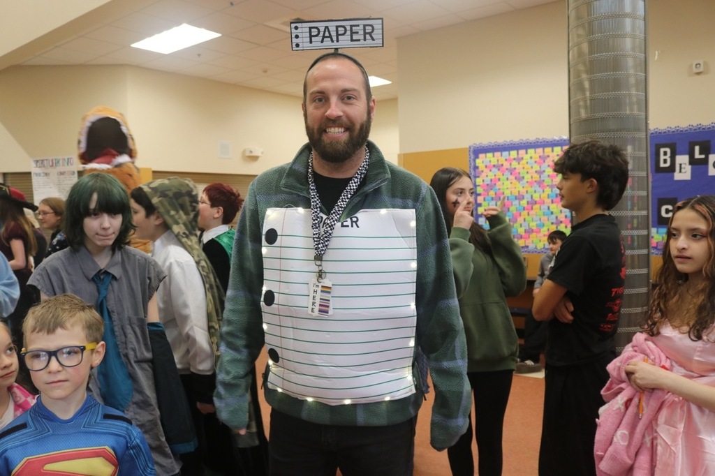 Evergreen Elementary School students dressed in Halloween costumes parade through the hallways of Cascade Middle School. Middle school students, many also in costume, line the hallways to exchange high fives and fist bumps with younger students. Other photos capture happy reunions between former Evergreen students and staff members.
