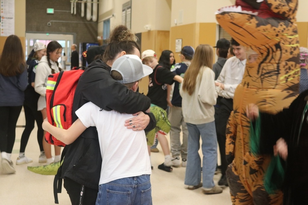 Evergreen Elementary School students dressed in Halloween costumes parade through the hallways of Cascade Middle School. Middle school students, many also in costume, line the hallways to exchange high fives and fist bumps with younger students. Other photos capture happy reunions between former Evergreen students and staff members.