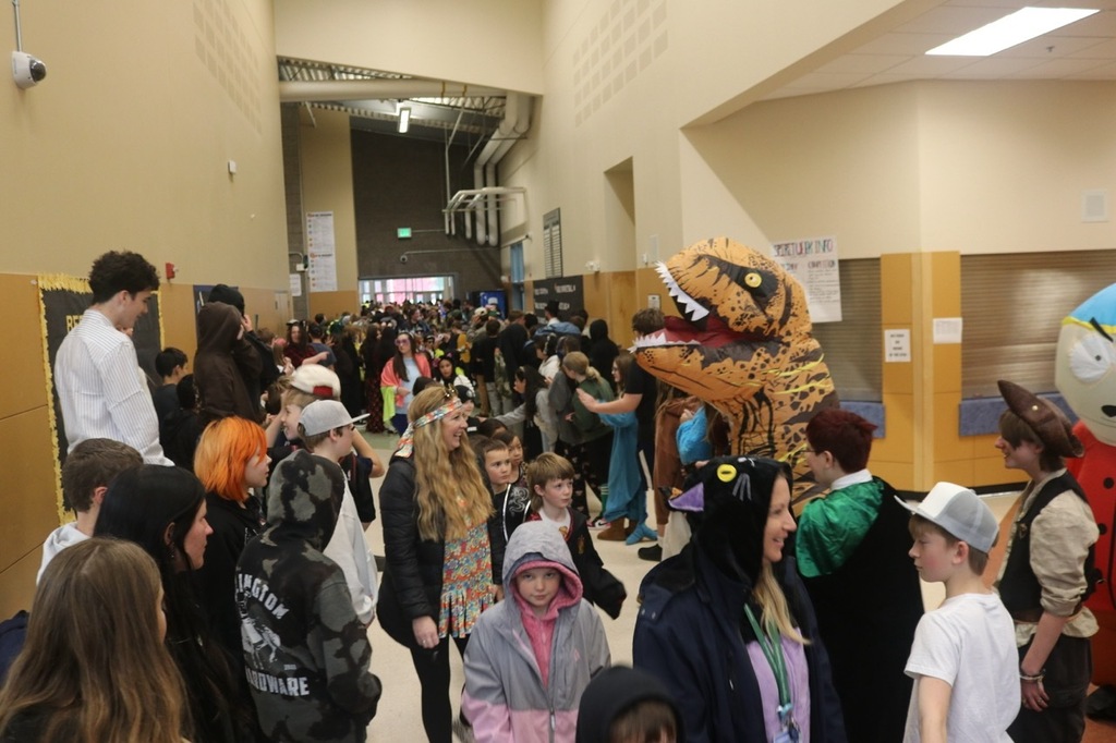 Evergreen Elementary School students dressed in Halloween costumes parade through the hallways of Cascade Middle School. Middle school students, many also in costume, line the hallways to exchange high fives and fist bumps with younger students. Other photos capture happy reunions between former Evergreen students and staff members.