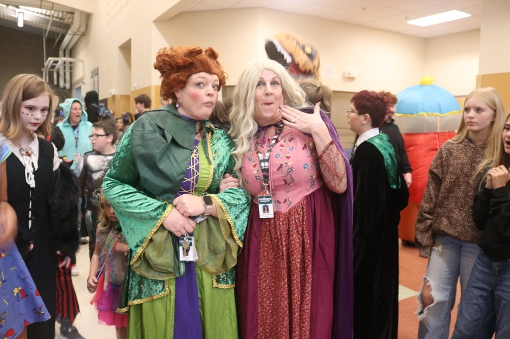 Evergreen Elementary School students dressed in Halloween costumes parade through the hallways of Cascade Middle School. Middle school students, many also in costume, line the hallways to exchange high fives and fist bumps with younger students. Other photos capture happy reunions between former Evergreen students and staff members.
