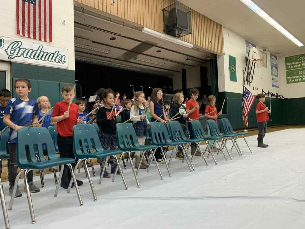 3rd graders drumming on chairs
