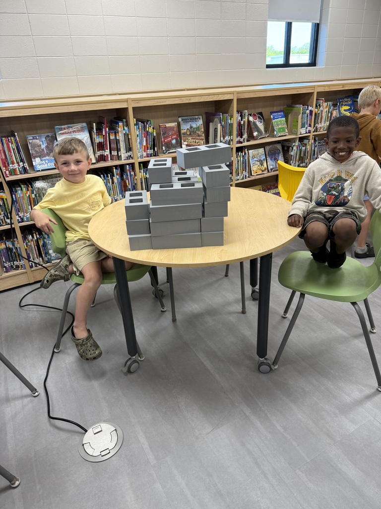 Miss Jodi Harper and Miss Jalee’ Conley’s class had an enrichment activity in the library. Mrs. Godwin read, “No Lie, Pigs (And Their Houses) Can Fly!” and a non fiction book about pigs. Students had to identify the characters and the setting of the story and the difference between fiction and non fiction texts. After the story, students had to create their own houses (setting) around a pig (character) taped to the tables. Items to build the houses included magnatiles, magnetic blocks, cups, dominoes, lincoln logs, fake bricks, and fake cement blocks. The idea was to make it strong enough not to get blown down. Miss Jodi used a hair dryer as the Big Bad Wolf. The class had lots of fun with this activity. 