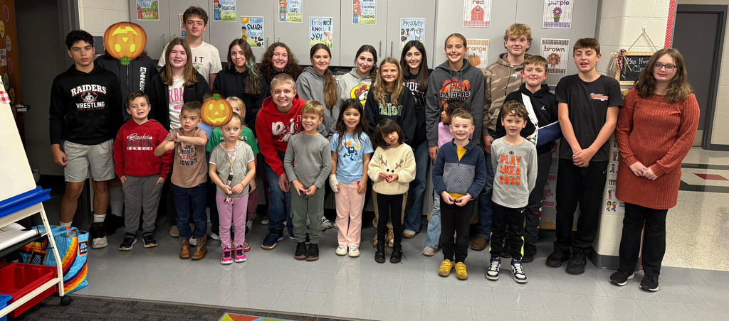 A group of eighth grade and kindergarten buddies stand together smiling.  